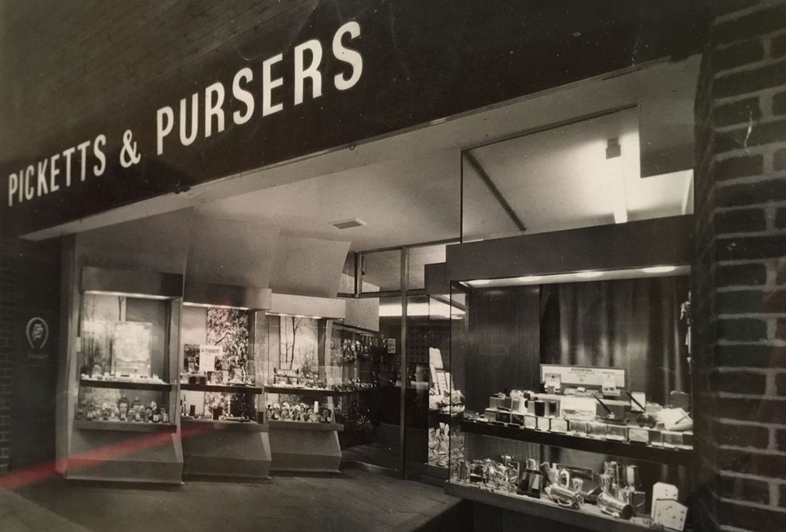 The shopfront lit after closing, at the head of the precinct.